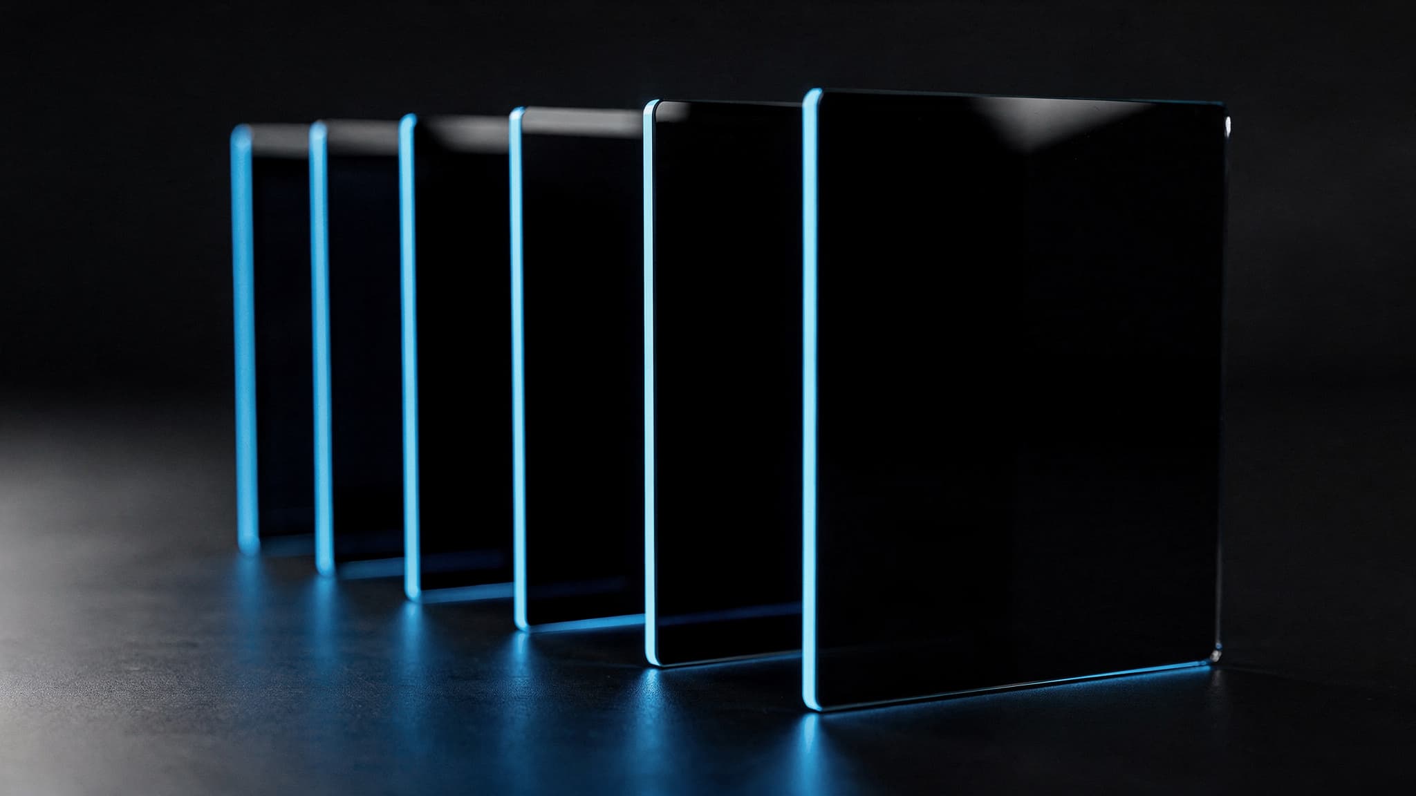 Seis láminas de vidrio negro alineadas en profundidad con el canto azul encendido, la primera nítida y las demás desenfocándose: los módulos se terminan de uno en uno.